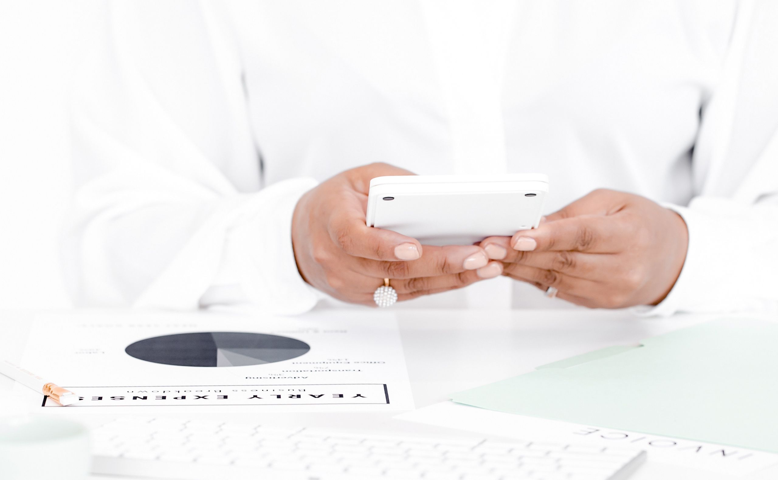 Image of black woman's handing holding a phone texting with work on the desk in front of her.